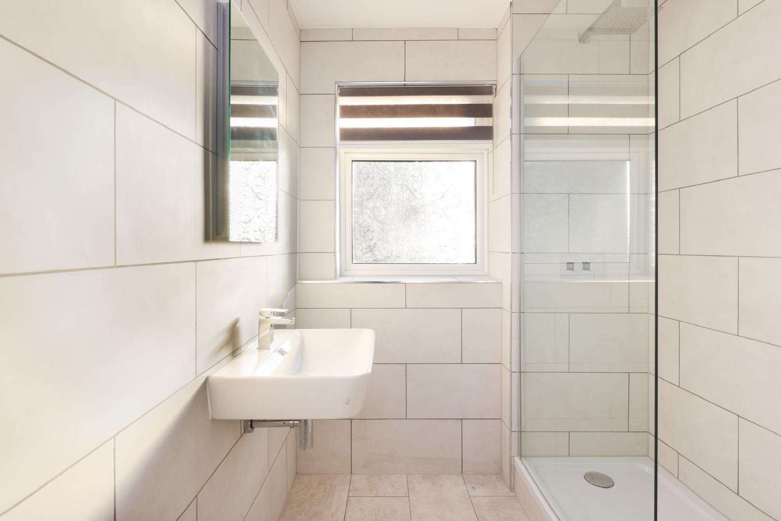 Modern panelled bathroom with black-framed walk-in shower and wood-effect vanity, London
